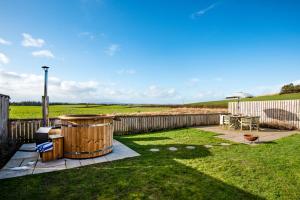 a backyard with a hot tub in the grass at Border View Cottage in Duddo