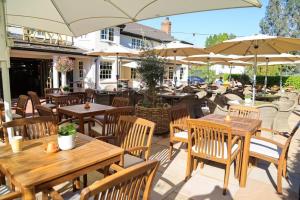 a patio with wooden tables and chairs and umbrellas at The Royal Foresters, Ascot, Berkshire - Acorn Pubs in Ascot