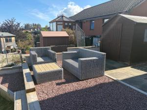two chairs and a table in a yard with a house at Firth View Heights, Luxury Detached Cottage with Stunning Panoramic View in Inverness