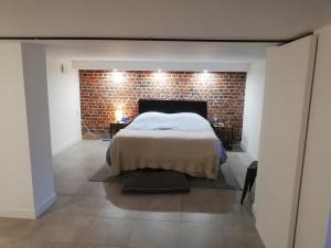 a bedroom with a bed and a brick wall at Souplex Michelet in Arras