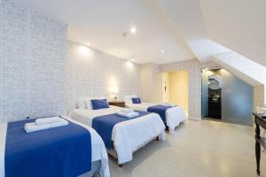 a hotel room with three beds with blue sheets at Casa Daupi Hotel Boutique in Mar del Plata +165 photos
