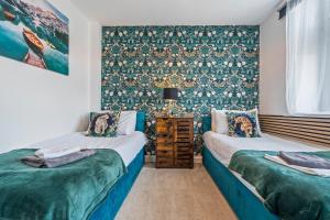 a bedroom with two beds and a wall covered in wallpaper at 3BR Pontypool Haven - Sleeps 6 with Parking in Pontnewynydd