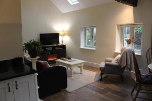 a living room with a tv and a couch and chairs at Charming Converted Stable in Ramsbury for Two in Ramsbury