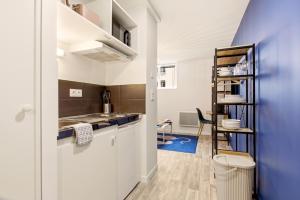 a kitchen with white cabinets and a blue wall at Studio L'Indigo - F1 design, hypercentre - CAEN in Caen +5 photos