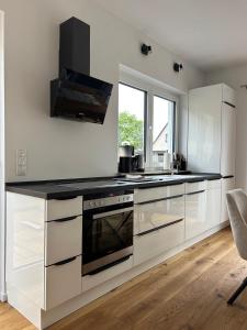 a kitchen with white cabinets and a black counter top at Haus am Meer mit Sauna in Koserow in Koserow +9 photos