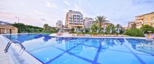 a large swimming pool with chairs and buildings at Hedef Resort Hotel - Ultra All Inclusive in Konaklı