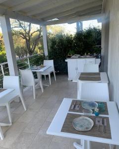 a patio with white tables and white chairs and a table at LIDO DEL FARO in Olbia