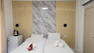 a bedroom with two beds with white sheets and a marble wall at אחוזת מונפלייר in Tiberias