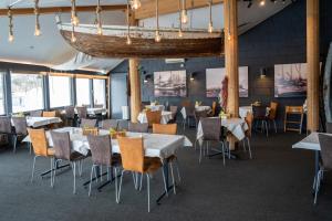 a dining room with tables and chairs and a chandelier at Fjellkysten in Tennevoll