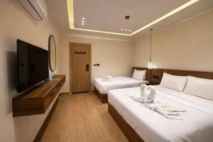 a hotel room with two beds and a flat screen tv at Cairo Stays Hotel in Cairo