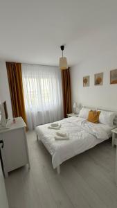a white bedroom with a large bed and a table at Apartament Luna in Şelimbăr