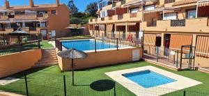 an apartment building with a swimming pool and an umbrella at A & G Casares Costa in San Luis de Sabinillas