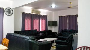 a living room with black leather furniture and purple curtains at My dad's cottage in Sekondi-Takoradi