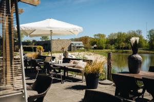 a patio with tables and chairs and an umbrella at Resort Land & Zee in Scharendijke +84 photos