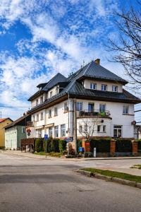 a large white house with a black roof at Hotel Chata ve Volarech Šumava in Volary