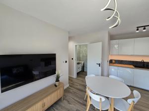 a kitchen and dining room with a white table and chairs at Apartamenty Miku - Łeba in Żarnowska