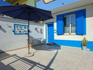 an umbrella in front of a building with blue doors at Blue Sicily Apartment in Roccalumera