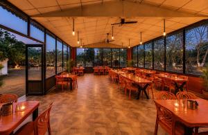 a restaurant with tables and chairs and large windows at Gir Wildtrack Lodge - Into the Deep Forest in Sasan Gir