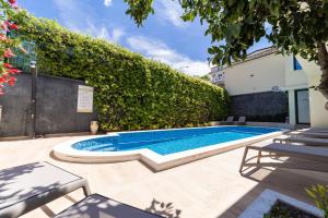 a swimming pool in a yard with a hedge at Klaris Guest house in Budva