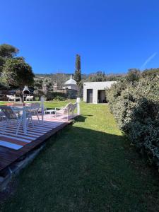 a deck with a table and chairs on the grass at Maison Erbalunga in Brando