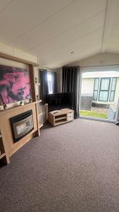 a living room with a flat screen tv next to a window at Lyons Robin Hood Hazel Park 6 in Rhyl