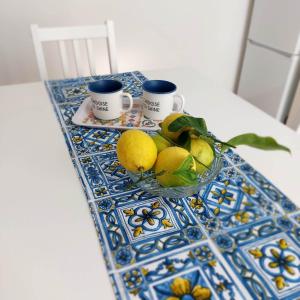 a table with two cups and a bowl of fruit at Blue Sicily Apartment in Roccalumera