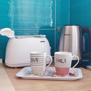 two coffee cups on a plate next to a toaster at Blue Sicily Apartment in Roccalumera
