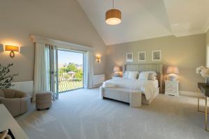 a white bedroom with a bed and a sliding glass door at Sea Estate House in Littlehampton