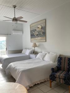 a bedroom with two beds and a couch and a fan at Queen Deluxe Double at Boundless Bliss Hotel in Raphune