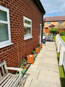 a brick building with a bench next to a sidewalk at Scarisbrick Apartment Sleeps 6 in Scarisbrick