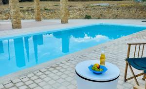 a drink and a bowl of fruit next to a swimming pool at Olive House Galaxidi in Galaxidi