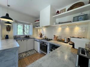 a large kitchen with white counters and white appliances at Tina`s House - Bordeira in Aljezur