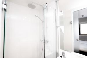 a white bathroom with a shower and a sink at Omena Hotel Jyväskylä in Jyväskylä