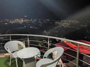 two chairs on a balcony with a view of a city at Siesta B&B Private Balcony & Himalayan Sunrise Views in Shimla +13 photos