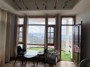 a room with a table and chairs and a large window at Siesta B&B Private Balcony & Himalayan Sunrise Views in Shimla
