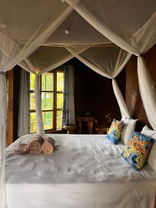 a bedroom with a large white bed with a canopy at Rutete Eco Lodge in Rwinkwavu