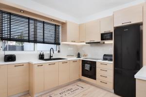 a kitchen with wooden cabinets and a black refrigerator at Aura Airport Suite in Spata