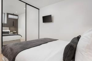 a bedroom with a white bed and a tv on the wall at Aura Airport Suite in Spata