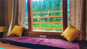 a window seat with a view of a mountain at Celestia Riverside Retreat in Manāli