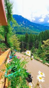 a view of a road with flowers on a balcony at Celestia Riverside Retreat in Manāli