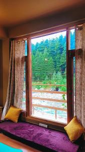 a window in a room with a view of a forest at Celestia Riverside Retreat in Manāli