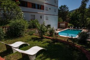 a house with a swimming pool and two white chairs at Hotel ITALIA in La Falda