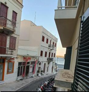 a street with a row of buildings next to the ocean at Helena's house in Ermoupoli