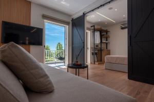 ein Schlafzimmer mit Bett, Fernseher und Balkon in der Unterkunft WALK2BEACH Riviera Beachfront Luxury Studio Suite - Steps to Yabanaki Varkiza in Varkiza