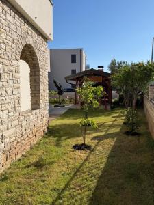 two trees in a yard next to a brick wall at Muring Apartments in Tribunj