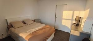 ein kleines Schlafzimmer mit Bett und Fernseher in der Unterkunft Appartement neuf avec balcon - Vue mer - Crozon in Crozon