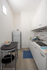 a white kitchen with a table and a refrigerator at Prestige House 6 in Scalea +4 photos