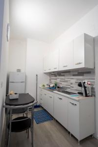 a kitchen with white cabinets and a table and a refrigerator at Prestige House 6 in Scalea