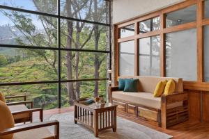 a living room with a couch and large windows at SaffronStays Blooming Stone in Kotagiri +15 photos
