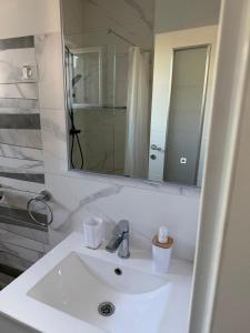 a white bathroom with a sink and a mirror at Muring Apartments in Tribunj +45 photos